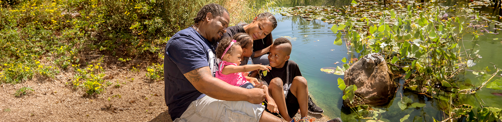 A family and their kids sitting by a pond