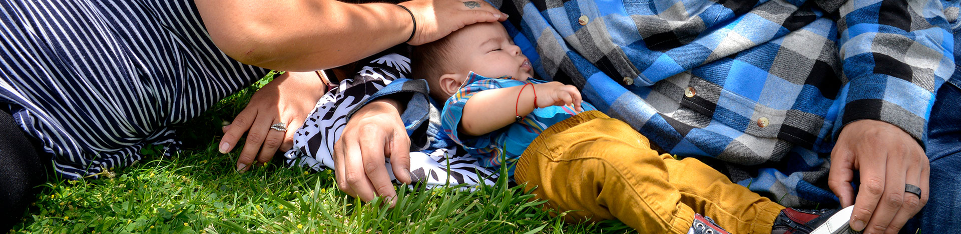 Close up of a mom and dad laying in the grass with their baby